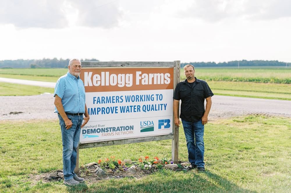 Kellogg Farms farmers standing by Kellogg Farms sign